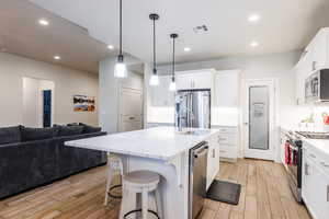 Kitchen featuring white cabinetry, open floor plan, appliances with stainless steel finishes, and recessed lighting