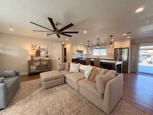 Living room featuring LVP floors, a textured ceiling, a ceiling fan, and recessed lighting