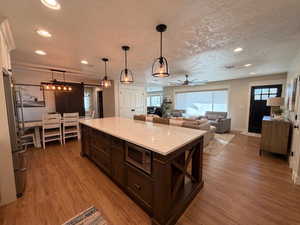 Kitchen featuring a barn door, recessed lighting, light stone countertops, light wood-type (LVP)  flooring, and pendant lighting