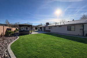 Rear view of property featuring a hot tub, a patio area, a fenced backyard, a gazebo, and stucco siding