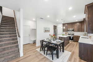 Dining space with light wood-style flooring, recessed lighting, and stairway