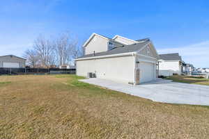 View of side of property with concrete driveway, roof with shingles, and a garage