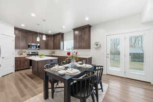 Kitchen featuring dark brown cabinets, hanging light fixtures, a kitchen island, light wood finished floors, and recessed lighting