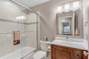 Bathroom with a textured wall, vanity, and shower / bath combination with glass door
