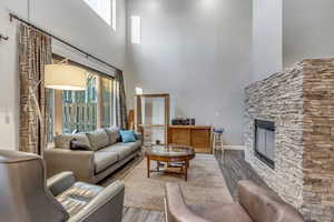 Living area with a stone fireplace, a high ceiling, and wood finished floors