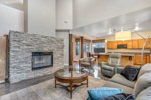 Living room featuring a fireplace, light wood-style floors, and a towering ceiling