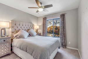 Bedroom with light carpet, a ceiling fan, and a textured wall