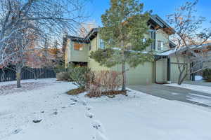 Snow covered property featuring a garage and concrete driveway