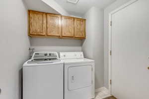 Laundry area with cabinet space, separate washer and dryer, a textured ceiling, and light tile patterned flooring