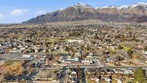 Aerial view of property and surrounding area featuring nearby suburban area and a mountainous background