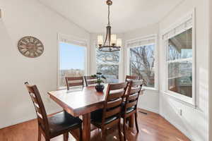 Dining room with light wood-style floors, healthy amount of natural light, a chandelier, and lofted ceiling