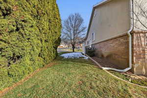 View of property exterior with brick siding, a yard, stucco siding, and a residential view