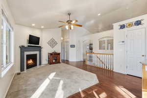 Living area featuring vaulted ceiling, a high end fireplace, dark wood finished floors, a ceiling fan, and recessed lighting