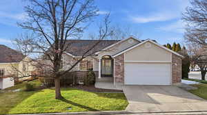 Ranch-style house featuring brick siding, a front lawn, concrete driveway, and an attached garage