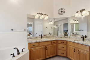 Owners suite bathroom featuring a bath, double vanity, and a high ceiling