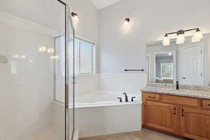 Owners suite bathroom featuring vanity, a garden tub, a shower stall, and healthy amount of natural light