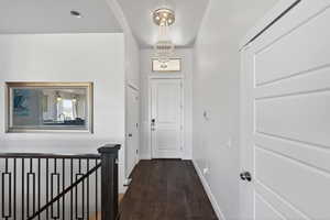 Hallway with a chandelier, dark wood-style floors, and an upstairs landing