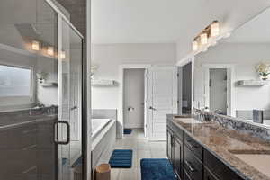 Bathroom featuring double vanity, a stall shower, a bath, and light tile patterned flooring