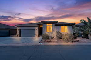 Prairie-style home featuring driveway, stucco siding, a garage, a tile roof, and stone siding