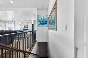 Corridor with recessed lighting, a textured ceiling, a chandelier, and an upstairs landing