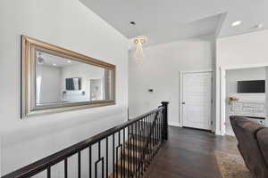 Hallway with dark wood finished floors, recessed lighting, an upstairs landing, and a chandelier
