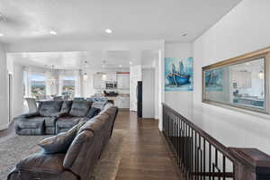 Living room with dark wood-style floors, a chandelier, recessed lighting, and a textured ceiling