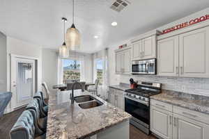 Kitchen with stainless steel appliances, dark stone counters, dark wood-type flooring, pendant lighting, and a kitchen bar