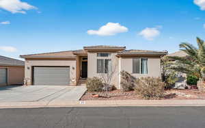 Prairie-style house featuring stucco siding, driveway, an attached garage, and a tile roof
