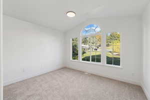 Unfurnished room featuring vaulted ceiling and light colored carpet