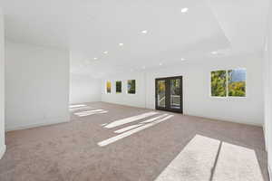 Spare room featuring plenty of natural light, light colored carpet, recessed lighting, and french doors
