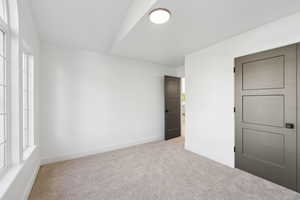 Unfurnished bedroom with light carpet and baseboards