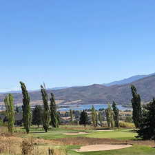 View of mountain background with a nearby body of water and a local golf course
