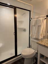 Full bath with a stall shower, vanity, and dark wood-style flooring