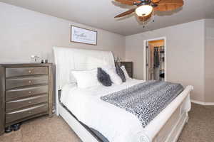 Bedroom featuring carpet flooring, a ceiling fan, and a spacious closet