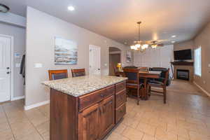 Kitchen with arched walkways, decorative light fixtures, light stone countertops, a chandelier, and a kitchen island