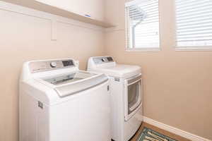 Laundry area with independent washer and dryer and baseboards