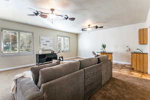 Family room with light colored carpet, ceiling fans, view to backyard and mountains.