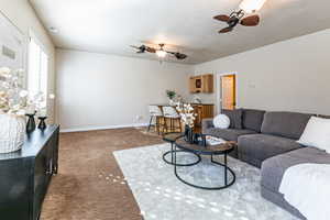 Family room with light colored carpet, ceiling fans, view to backyard and mountains.