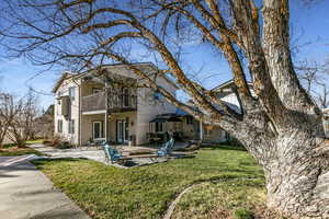 Rear view of house featuring a patio, a lawn,  and a balcony.
