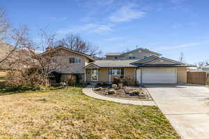 View of front of house featuring concrete driveway, brick siding, a garage, a metal roof.