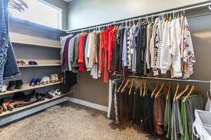 Primary bedroom walk in closet with carpet