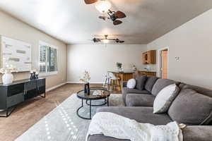 Large carpeted family room featuring ceiling fan, wet bar,  bathroom, door out to covered patio and hallway to laundry room and mudroom entry from garage.