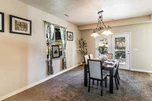 Dining room with dark carpet, a textured ceiling, and french doors