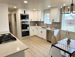 Kitchen with white cabinetry, appliances with stainless steel finishes, light stone countertops, and recessed lighting