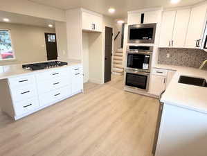 Kitchen with light stone counters, white cabinets, recessed lighting, appliances with stainless steel finishes, and decorative backsplash