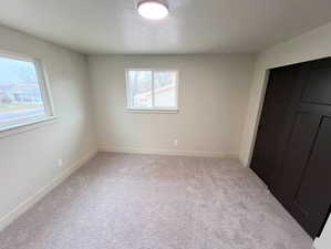 Unfurnished bedroom featuring light carpet and baseboards