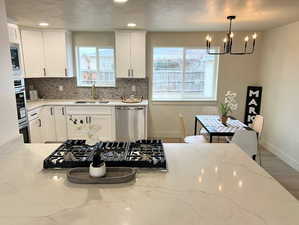 Kitchen with light stone counters, stainless steel appliances, white cabinetry, a textured ceiling, and recessed lighting