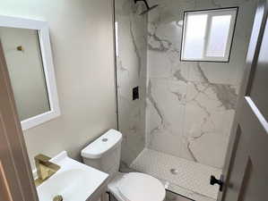 Bathroom featuring vanity and a marble finish shower