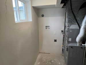 Washroom featuring concrete floors, heating unit, hookup for a washing machine, and hookup for an electric dryer