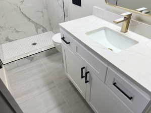 Full bath featuring vanity and a marble finish shower